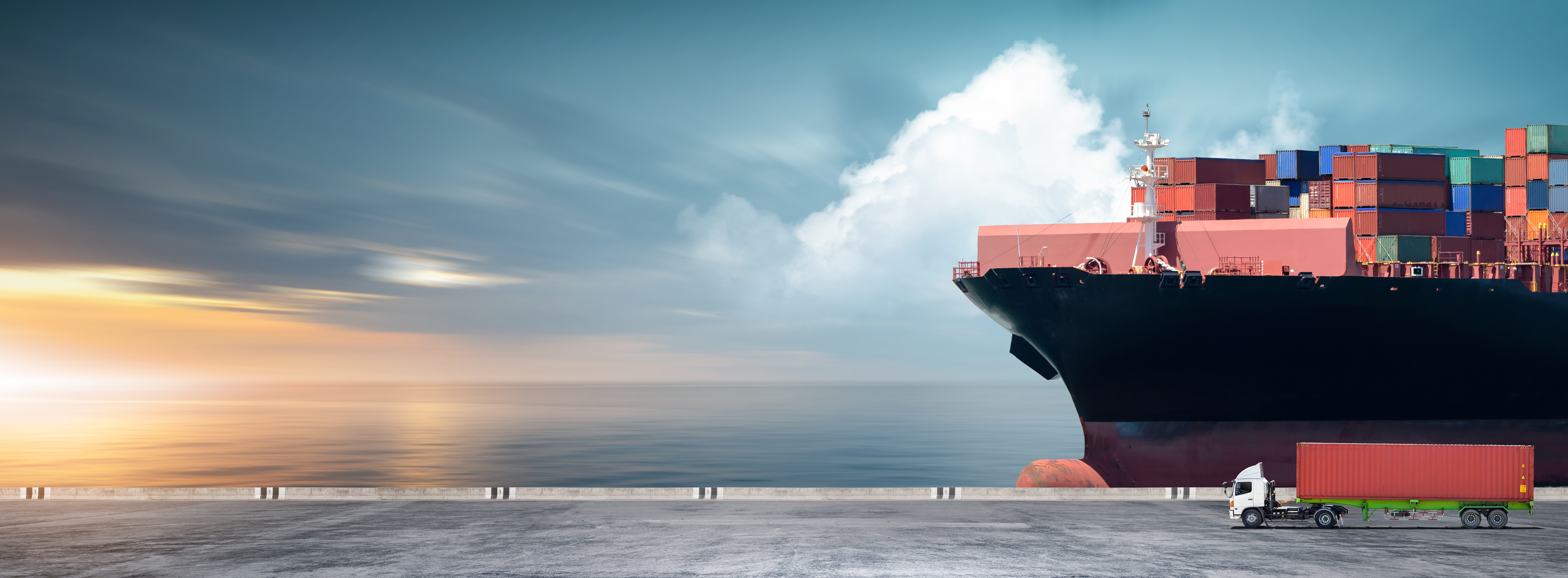 Cargo ship with containers and semi-truck at a port during sunset.